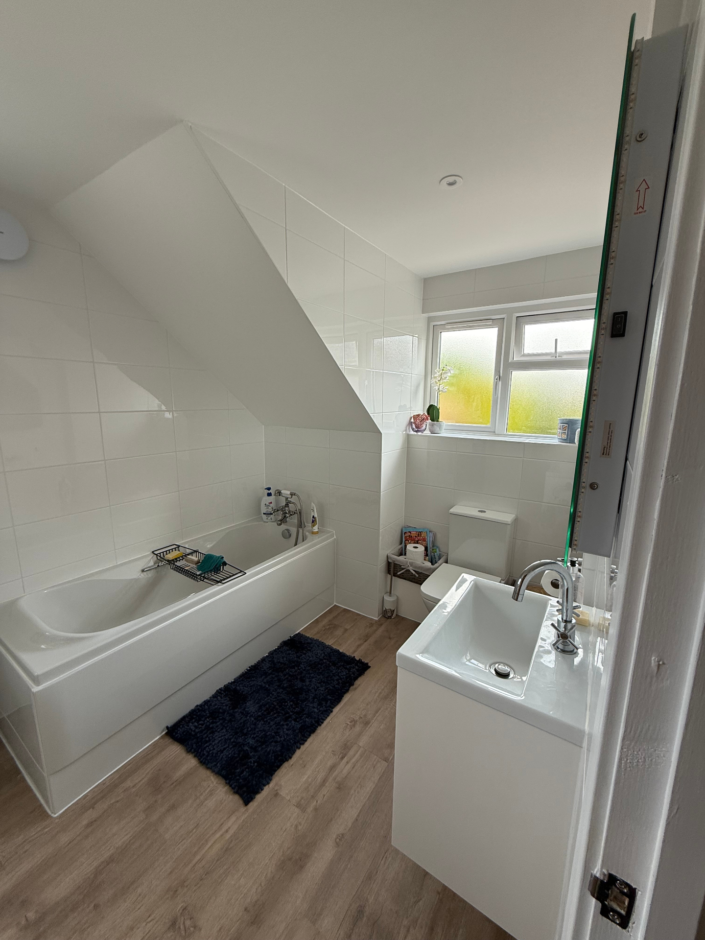 Finished new build family bathroom with white suite, bath, basin and wood effect flooring by A Baker Construction West Sussex